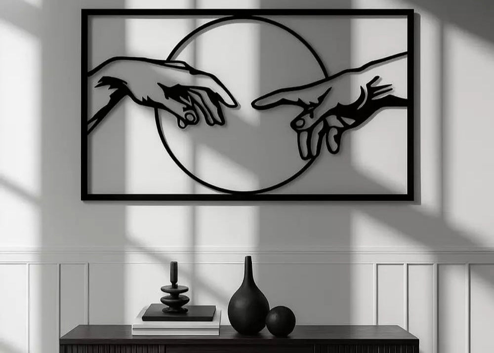 Framed artwork of two hands reaching towards each other on a wall with a console table below.